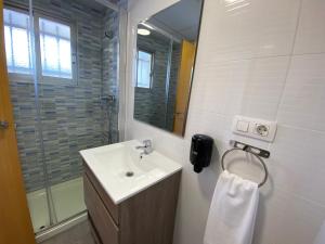 a bathroom with a sink and a shower with a mirror at Pensión La Ola in Grao de Castellón