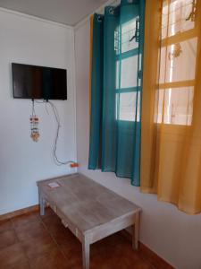 a room with a table and a tv on a wall at MAISON DE VACANCES KAZ A LOLO in Port-Louis
