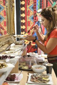 a woman standing at a buffet with plates of food at The Sydney Hotel in Amman