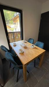 a wooden table with blue chairs and a window at Apartma Zala, Golte in Mozirska Koča