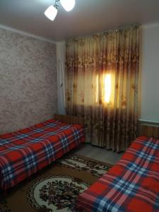 um quarto com 2 camas e uma janela com cortinas em SunRay Guest House-Hostel em Karakol