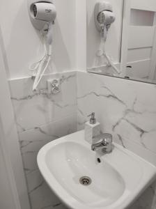 a white bathroom with a sink and a mirror at Hostel 36 in Katowice
