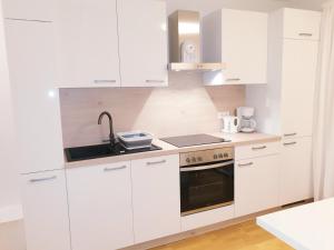 a white kitchen with a sink and a stove at Appartement Fiffinjo in Piesendorf