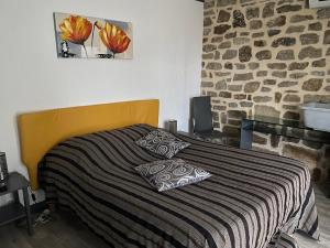 ラ・テュルバルにあるGîtes et Chambres - Les Buissonnetsのベッドルーム1室(黄色のヘッドボードと石壁のベッド1台付)