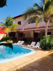 een zwembad naast een huis met palmbomen bij Manitu Flat Canoa Quebrada in Canoa Quebrada