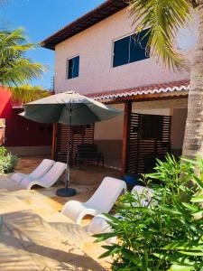 a group of chairs and an umbrella in front of a house at Manitu Flat Canoa Quebrada in Canoa Quebrada