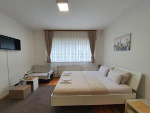 een slaapkamer met een groot wit bed en een bank bij Studio Apartman 11 in Bihać