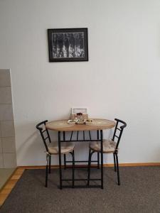 stół z dwoma krzesłami i zdjęciem na ścianie w obiekcie Studio Apartman 11 w mieście Bihać
