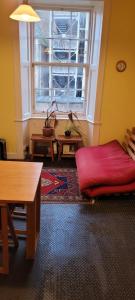a living room with a red couch in front of a window at City centre Flat - sleep upto 4 in Edinburgh