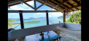 a room with a table and a view of the ocean at Sítio Promontório - Casa Grécia in Ubatuba