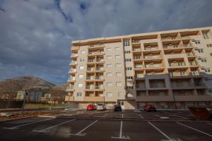 a large apartment building with cars parked in a parking lot at Apartman Iskra in Trebinje