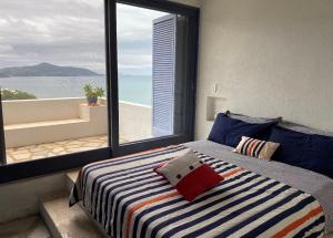 a bedroom with a bed with a view of the ocean at Sítio Promontório - Casa Grécia in Ubatuba