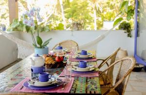 a table with plates of food and a vase of flowers at Sítio Promontório - Casa Grécia in Ubatuba
