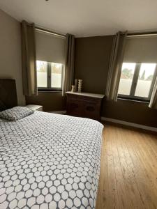 a bedroom with a white bed and two windows at Vakantiewoning Bij de Jep in Bilzen