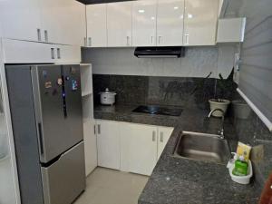 eine Küche mit weißen Schränken und einem Kühlschrank aus Edelstahl in der Unterkunft Simang’s Guest House in General Santos