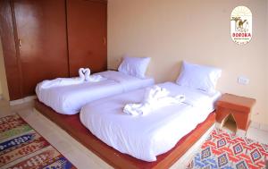 dos camas sentadas una al lado de la otra en una habitación en DoroKa Nubian House en Ash Shallāl