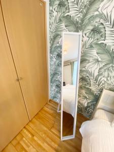 a mirror in a bedroom with a tropical wallpaper at ラ・フィットヤマト101 in Meinohama
