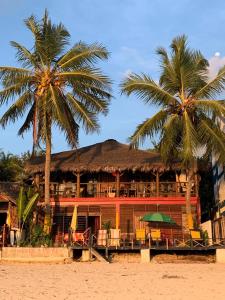 een gebouw op het strand met twee palmbomen bij villa Mena in Nosy Be