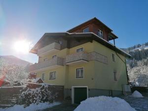 a yellow house with a green door in the snow at Haus Schober in Bad Hofgastein