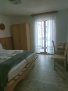 a bedroom with a bed and a sliding glass door at Agritur Maso Flonkeri in Bosentino