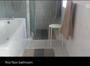 uma casa de banho com uma banheira, um chuveiro e um banco em Double Rooms in Shared Home em Enfield