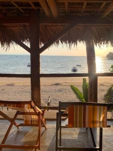 a view of the beach with two chairs and an umbrella at villa Mena in Nosy Be