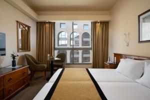 una camera d'albergo con letto, scrivania e finestra di Olive Tree Hotel a Gerusalemme