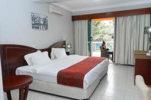 een hotelkamer met een bed en een vrouw in een stoel bij Mendiata Hotel in Accra