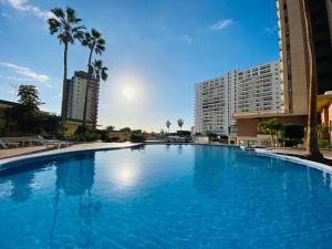 a large blue swimming pool with palm trees and buildings at Sunset Paradise in Adeje