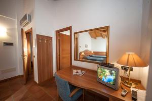 Zimmer mit einem Schreibtisch, einem TV und einem Spiegel in der Unterkunft La Vigneta in Arsiero