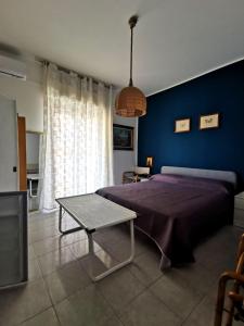 a bedroom with a bed and a table and a blue wall at B&B Di Marco in Giardini Naxos