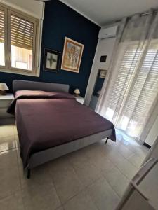 a bedroom with a bed and blue walls and windows at B&B Di Marco in Giardini Naxos