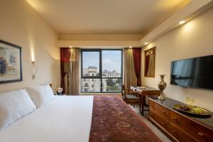 Cette chambre comprend un lit et une grande fenêtre. dans l'établissement Olive Tree Hotel, à Jérusalem