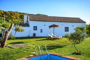 ein weißes Haus mit einem Garten mit Pool in der Unterkunft Cortijo las Cabrerizas in Facinas