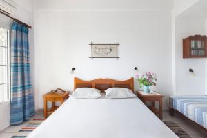 a bedroom with a large white bed and two tables at DELFINI I in Fira