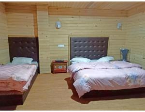 2 camas en una habitación con paredes de madera en Cherry Village Resort, Pelling, Sikkim, en Pelling