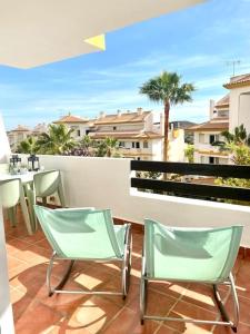 米哈斯科斯塔的住宿－Wonderful appartement on golf site near Marbella，阳台配有两把椅子和一张桌子,位于庭院