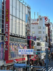 uma rua movimentada da cidade com edifícios altos e placas em Shinokubo guest house em Tóquio