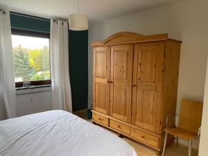 a bedroom with a large wooden cabinet and a window at Die HarzSchrittMacher - Bergmann 24 in Bad Harzburg