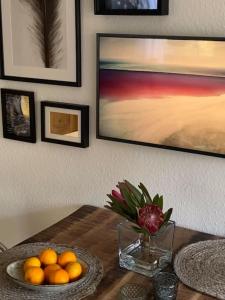 a table with a bowl of oranges and a vase of flowers at Die HarzSchrittMacher - Bergmann 24 in Bad Harzburg