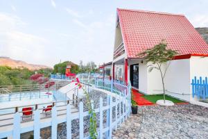 a house with a white fence and a pool at Red_Hut_Resort in Hatta