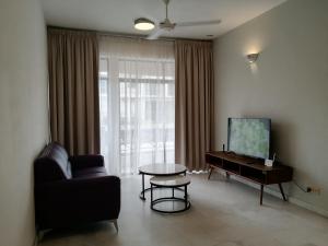 uma sala de estar com um sofá, uma televisão e uma mesa em City Tropical Home I em George Town