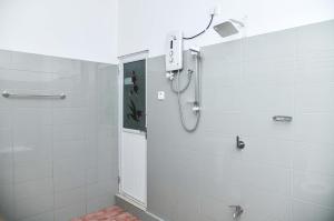 a shower in a bathroom with white tiles at Clay House in Udawalawe