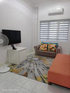 Santorini by Loteloft at Bukit Merah Laketown في Simpang Ampat Semanggol: غرفة معيشة مع أريكة وتلفزيون بشاشة مسطحة