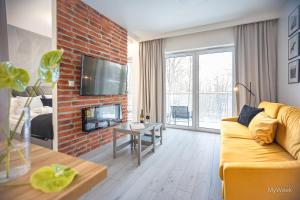 een woonkamer met een bank en een stenen open haard bij Apartament z kominkiem.. and SPA, MyWeek in Polanica-Zdrój