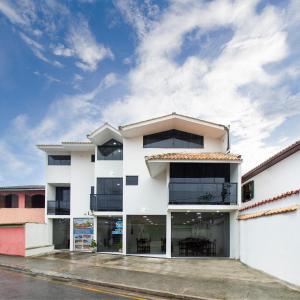 a white building with black windows on a street at Pousada Lagoa Azul in Paraty
