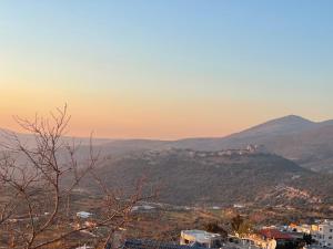 una vista de una ciudad en una montaña al atardecer en צימר מעל העננים, en Ein Kinya