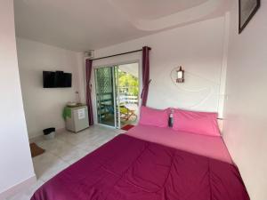 Cama rosa en habitación con puerta corredera de cristal en Winnerview Zone B en Ko Larn