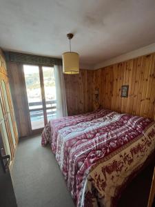 a bedroom with a bed and a large window at Sèn jan apartment 150 mt dalle piste in Pozza di Fassa