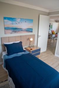 um quarto com uma cama azul e uma sala de estar em Ap Cozy Calhau prox PRAIA em São Luís